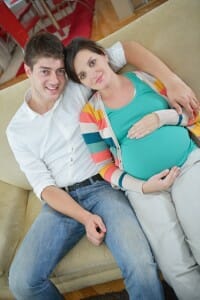 pregnant couple at home using tablet computer